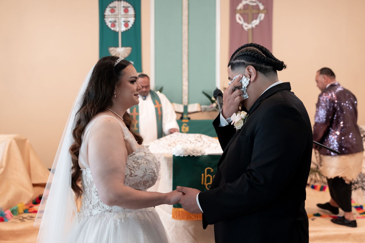 A couple exchanges vows during their wedding ceremony in a room with turquoise accents and peach walls.