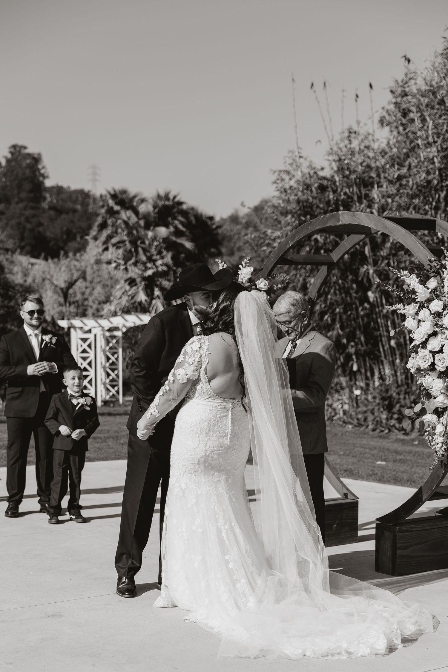 A romantic wedding ceremony moment captured in black and white as the couple exchanges vows in a garden setting.