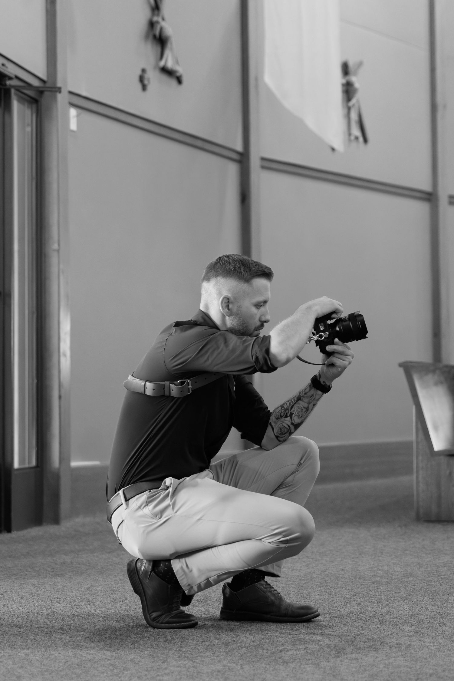 Professional photographer in a crouching position taking photos with a digital camera.