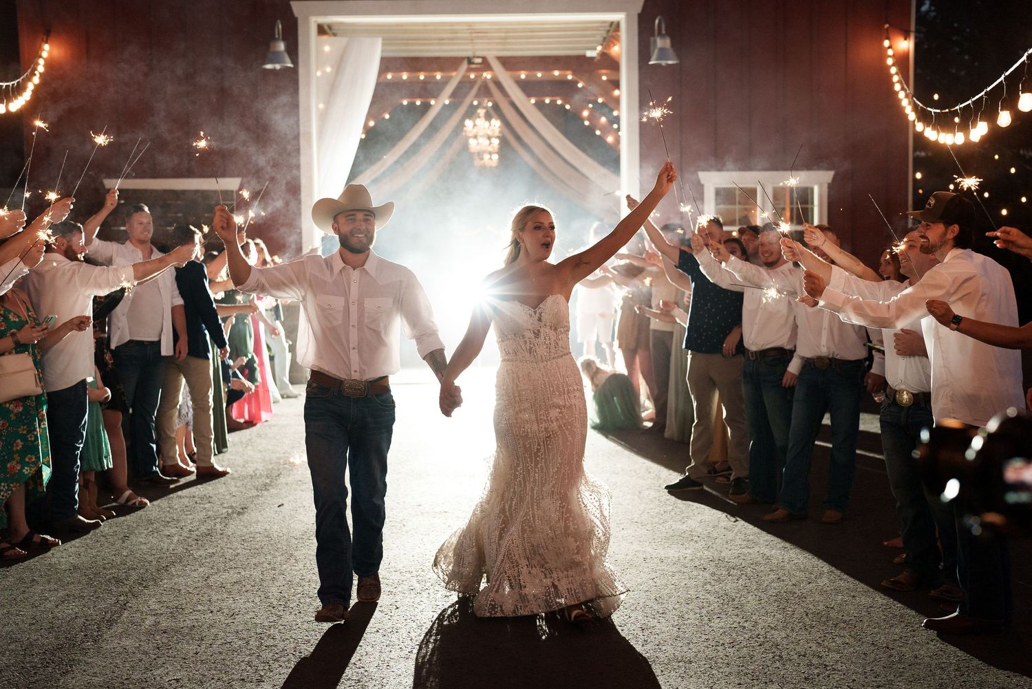 Wedding exit with sparklers lighting up newlyweds walking through guest tunnel.