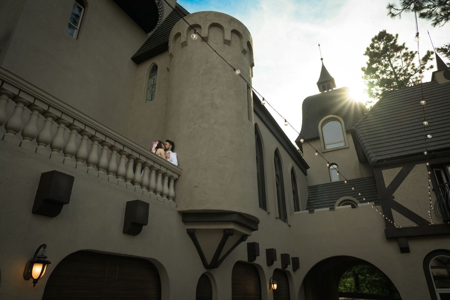 Castle-like venue photographed from below with sunburst through tower spires.