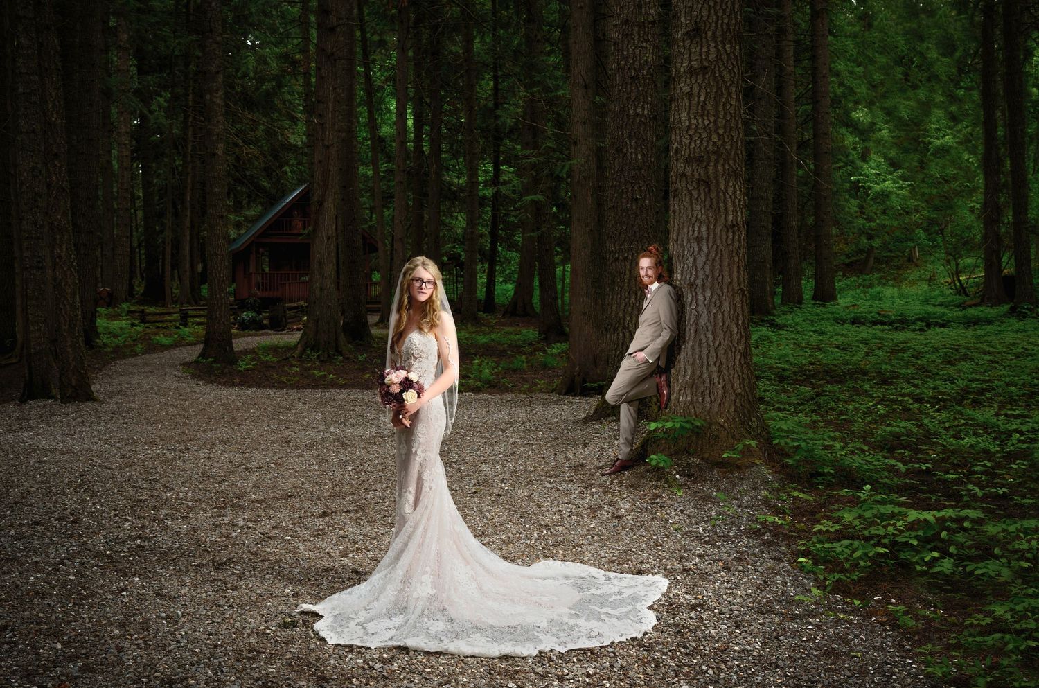 A romantic wedding photo in a forest with a flowing white lace dress and dramatic lighting.