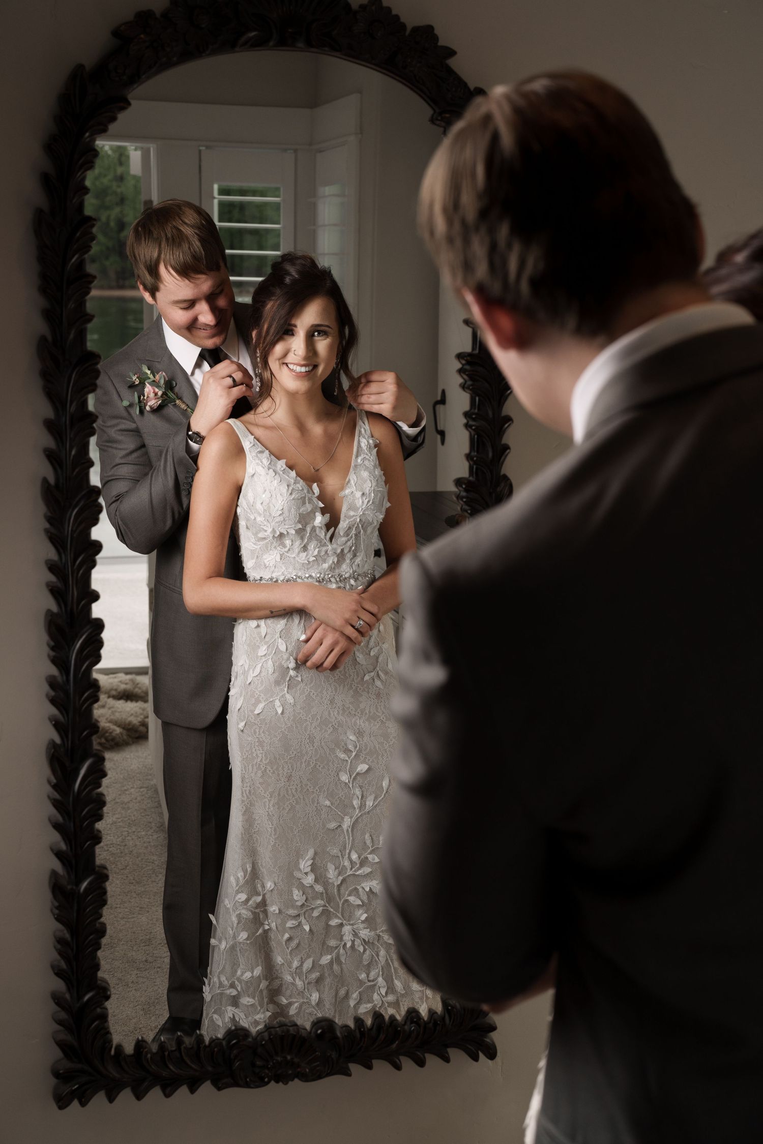 Wedding couple reflected in an ornate black mirror frame during an intimate indoor moment.
