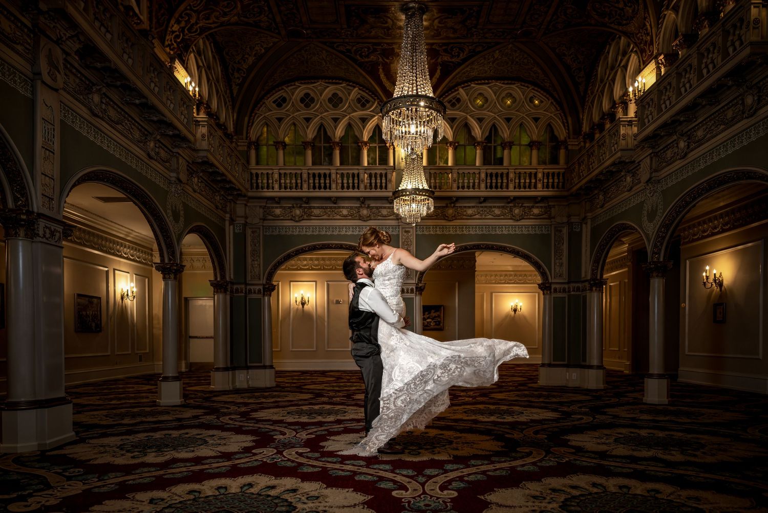 Dramatic dance dip pose in ornate ballroom with classical architecture and warm lighting.