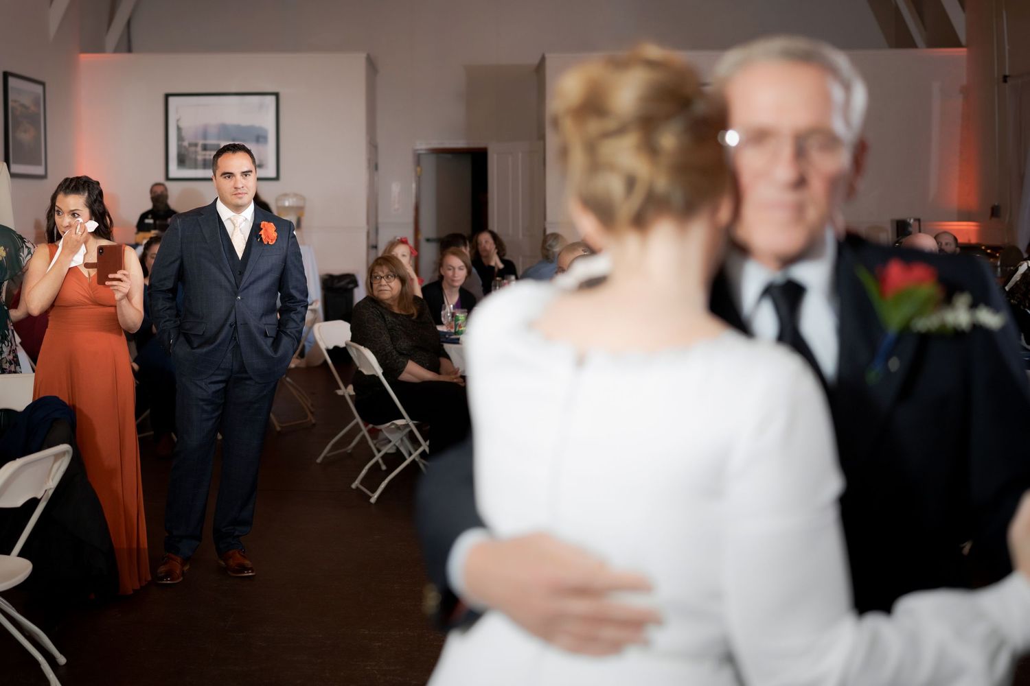 Wedding celebration in a hall with guests watching from folding chairs.
