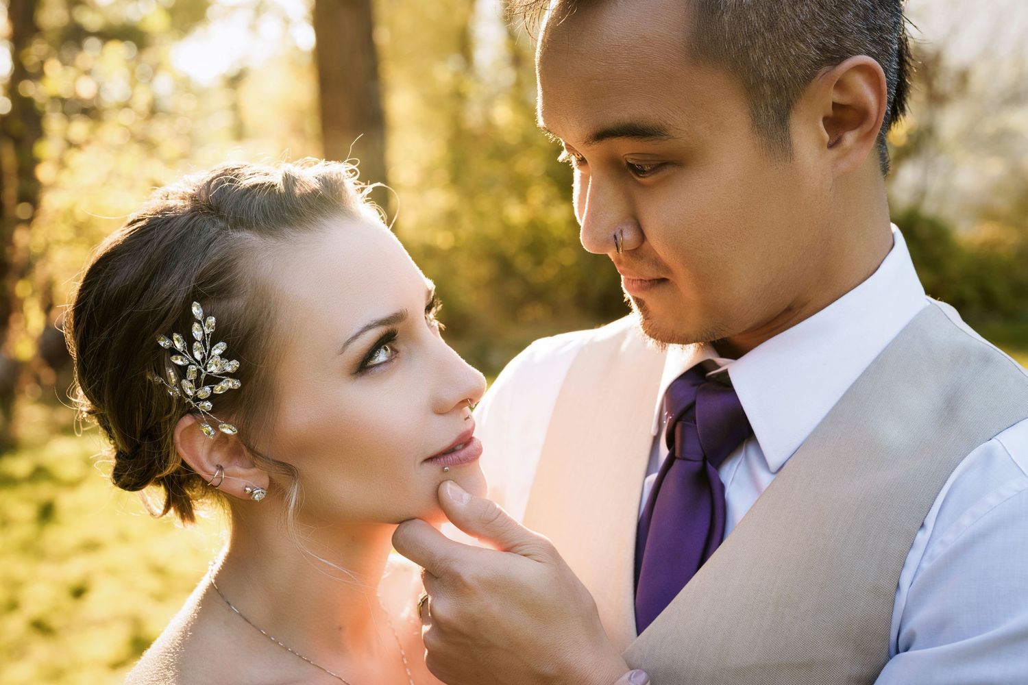 Wedding couple in soft evening sunlight with delicate hair accessories.