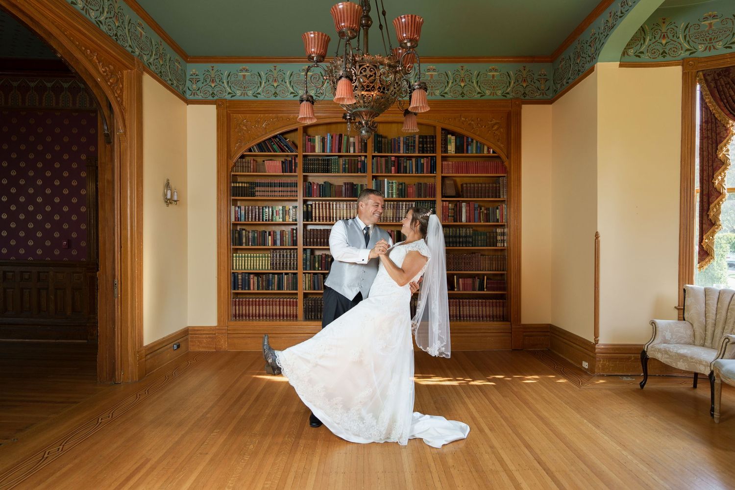 Elegant dance pose in a grand library with ornate decor and bookshelves.