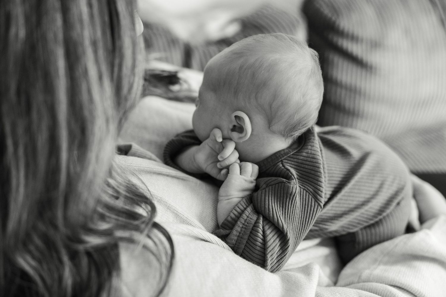 A series of black and white intimate photographs showing tender moments between parent and newborn baby.