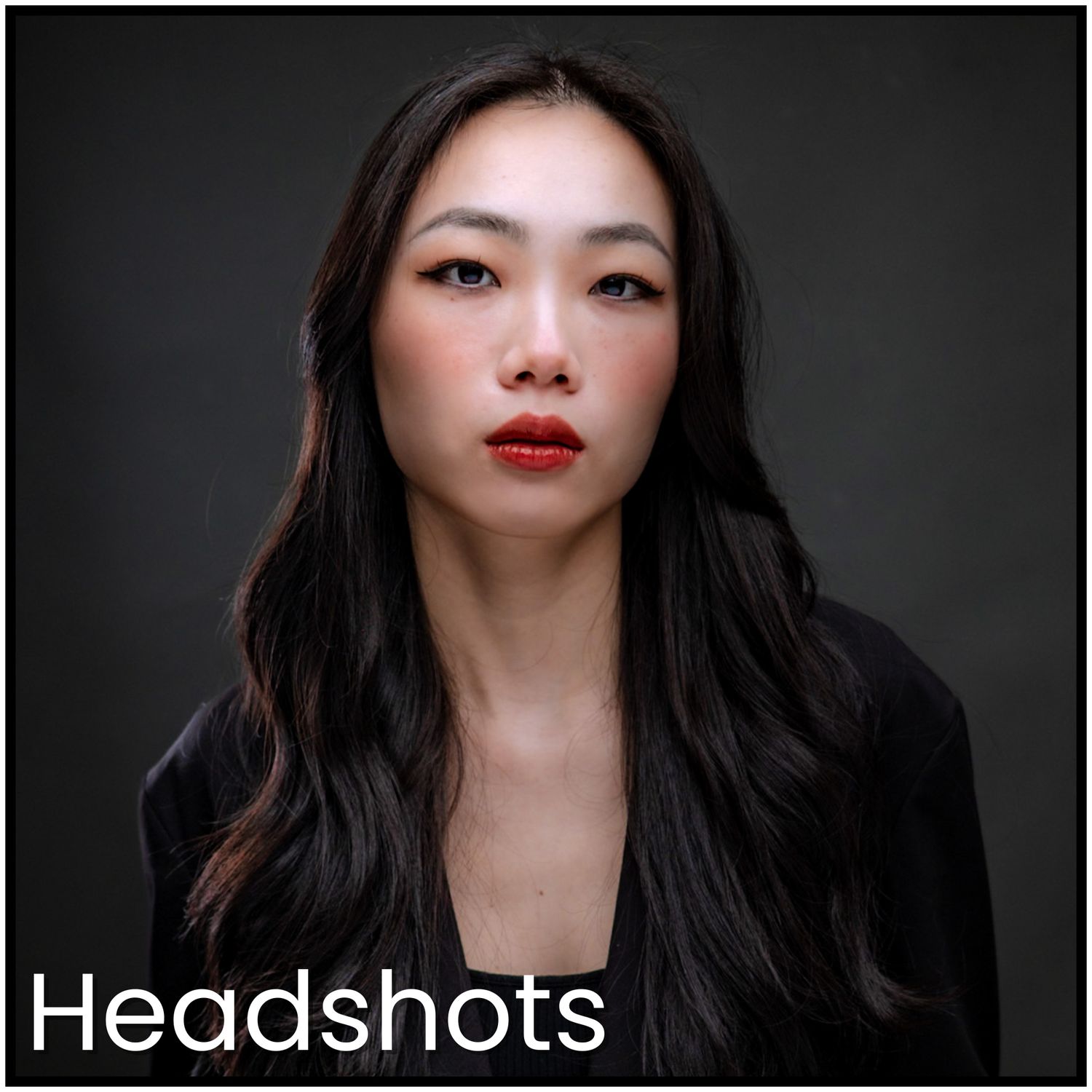 Professional beauty portrait with dramatic lighting against dark background featuring red lipstick and long dark hair.
