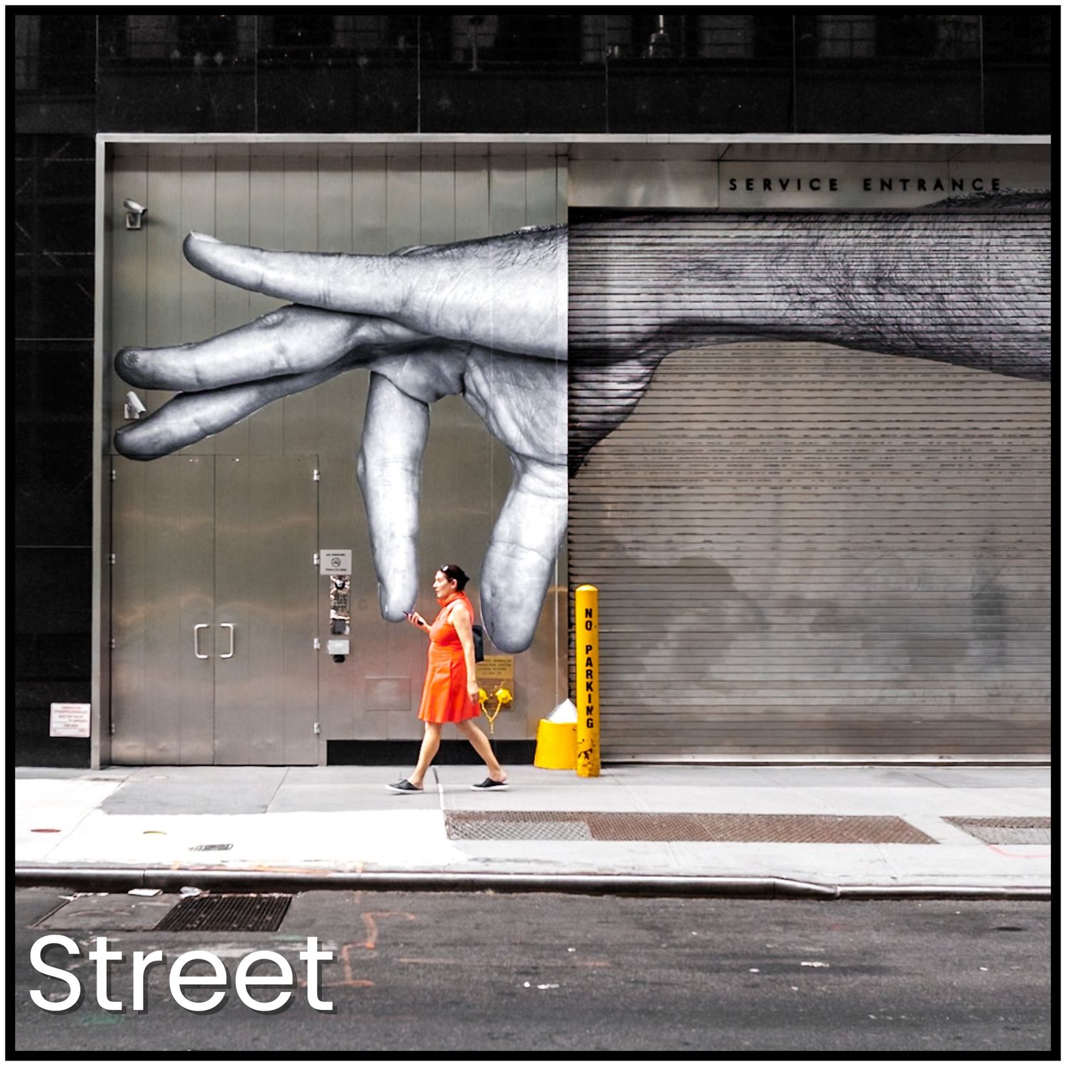 Street art mural shows giant hand reaching down toward small figure in orange dress standing on sidewalk.
