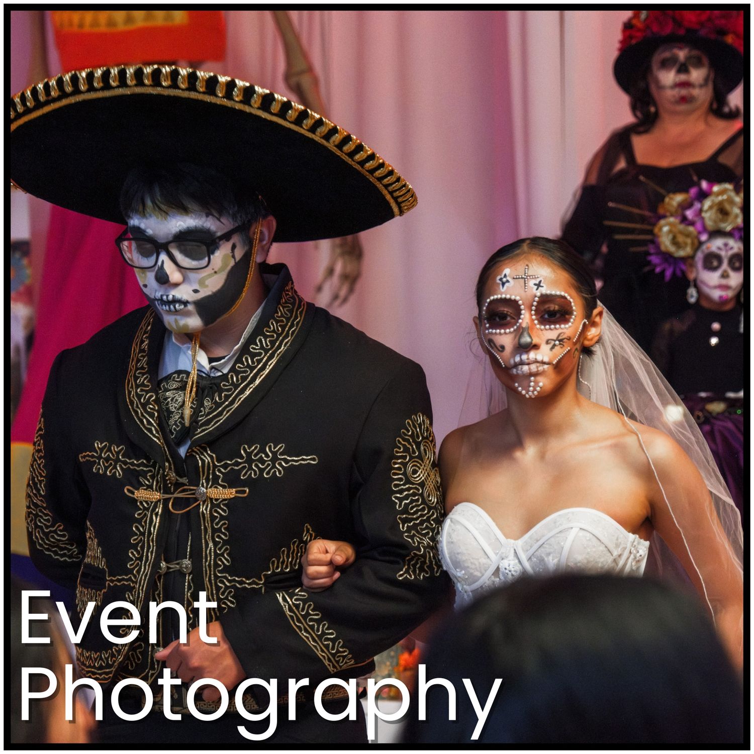 A couple in Dia de los Muertos sugar skull face paint and wedding attire pose together at an event.