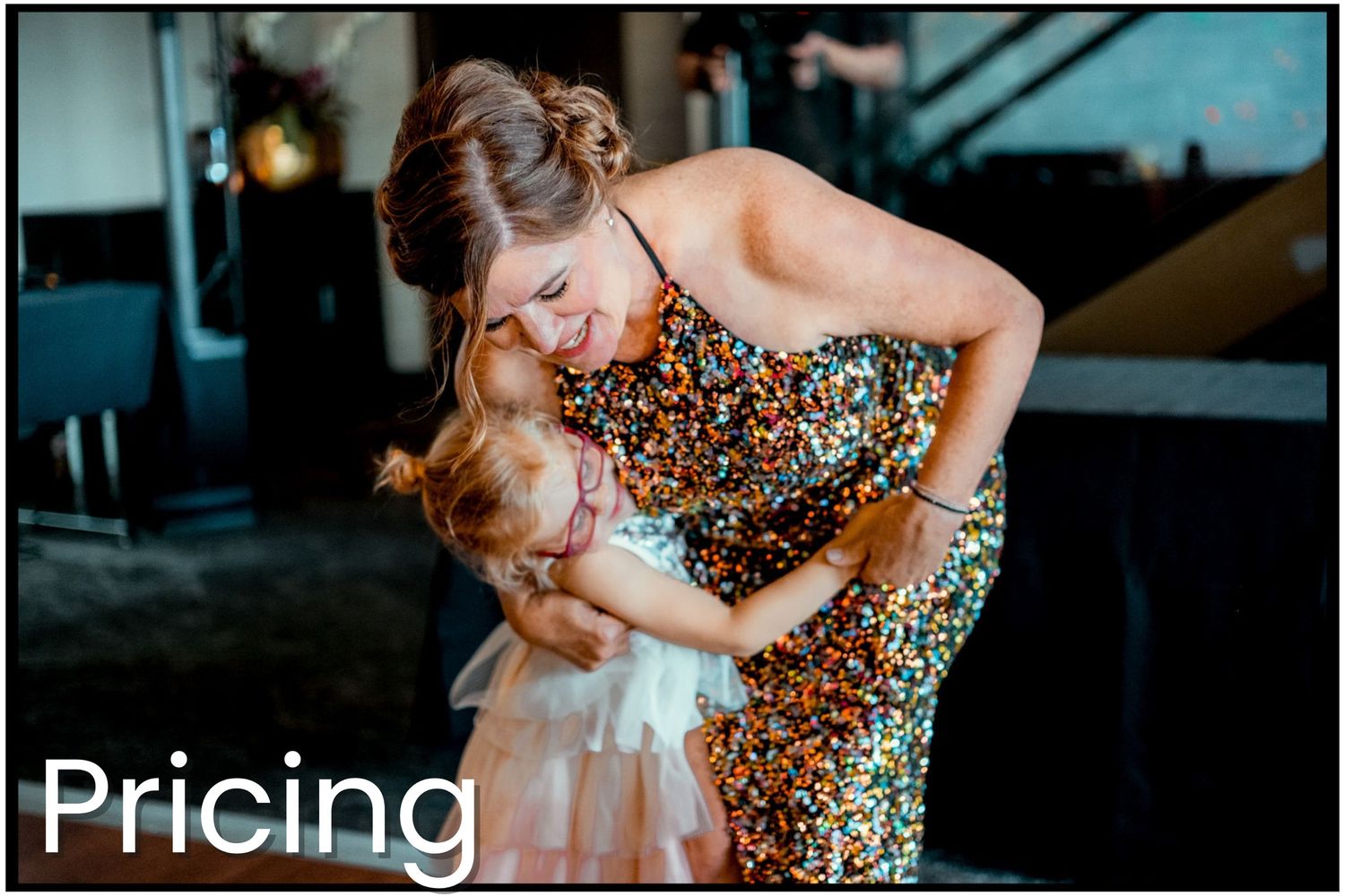 A person in a sparkling gold evening gown embracing a young child in a soft white dress during a special event.