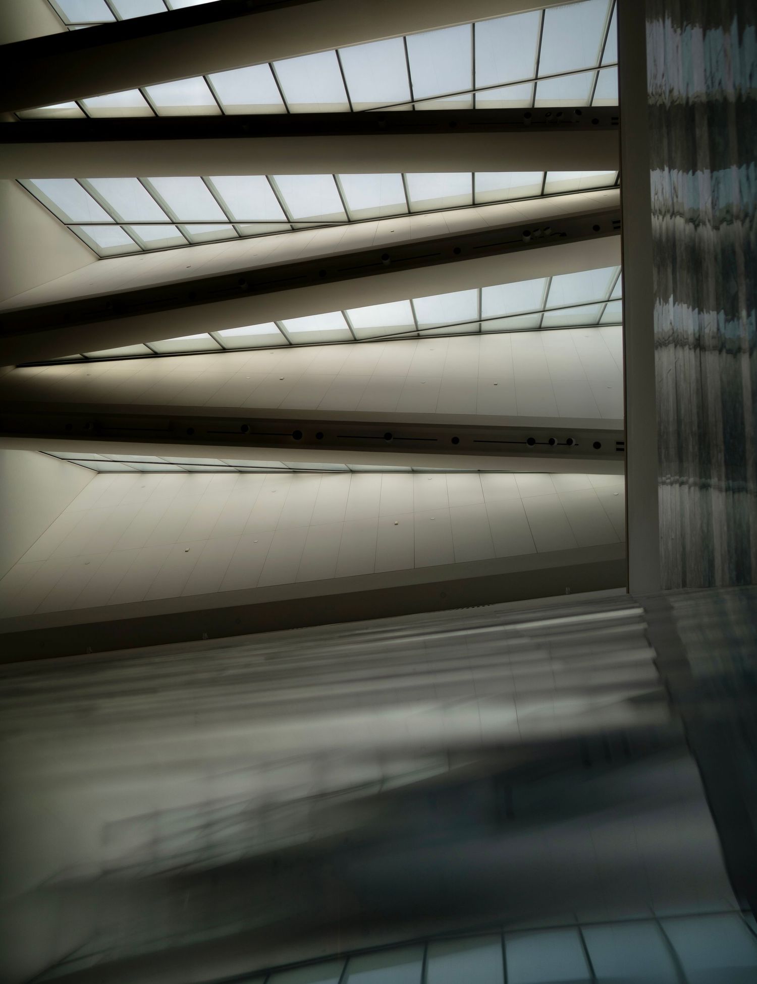 Abstract architectural interior with angled skylights creating dramatic shadows.