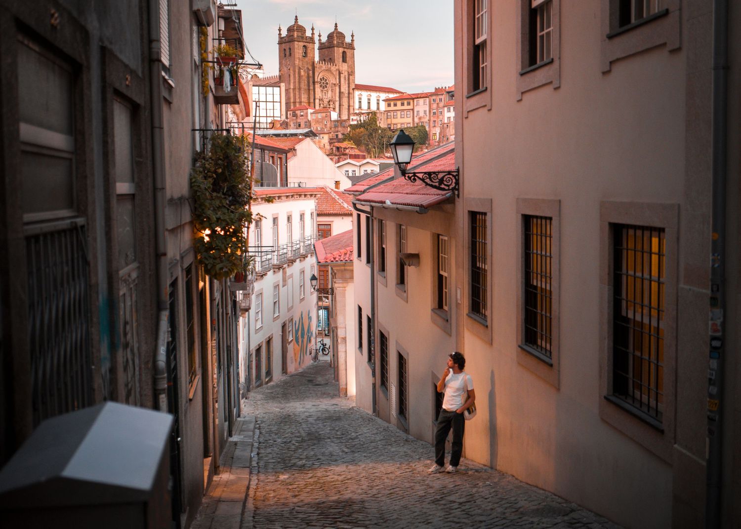 Narrow cobblestone alley leading to historic church towers in Porto's old town.