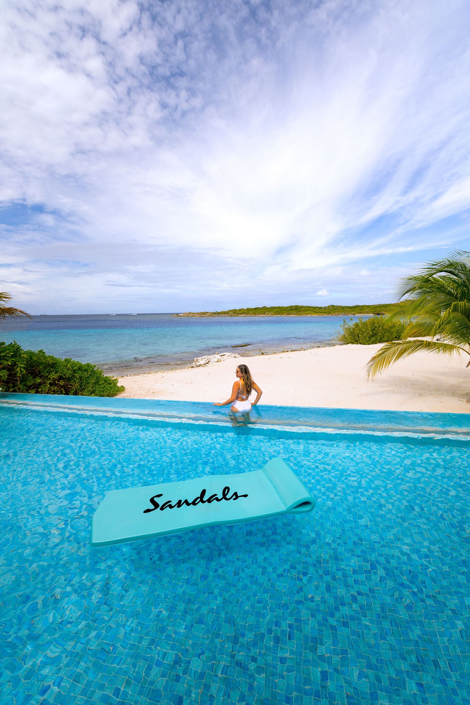 Luxurious Sandals resort infinity pool overlooking a pristine Caribbean beach.