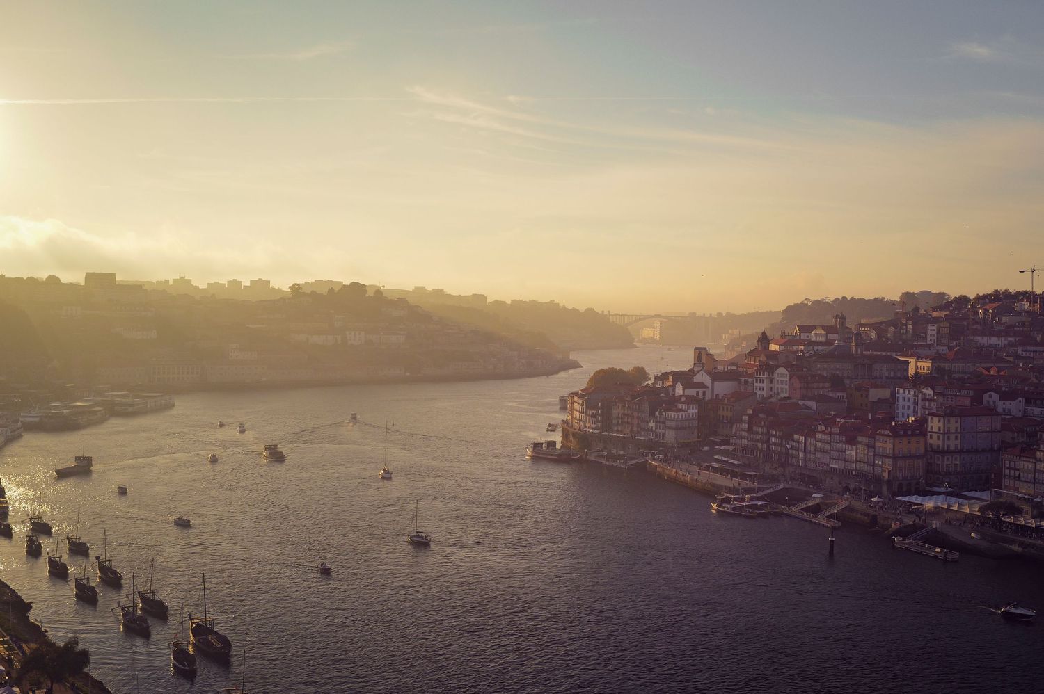 Golden sunset over Porto's waterfront with boats dotting the harbor.