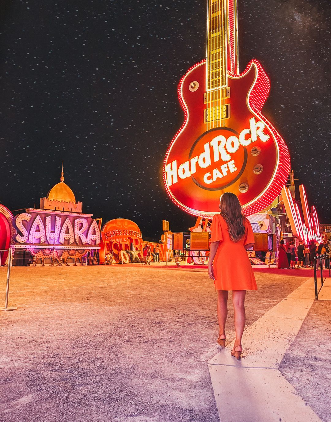 Iconic Hard Rock Cafe neon guitar sign illuminates the Las Vegas strip at night.