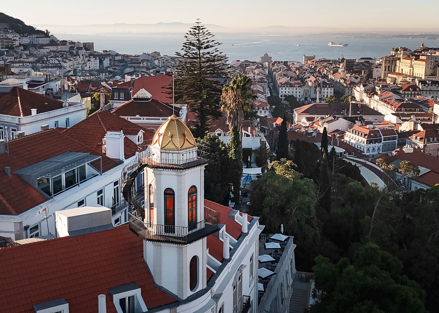 Panoramic cityscape view of Porto with traditional red-tiled roofs and church towers at sunset.