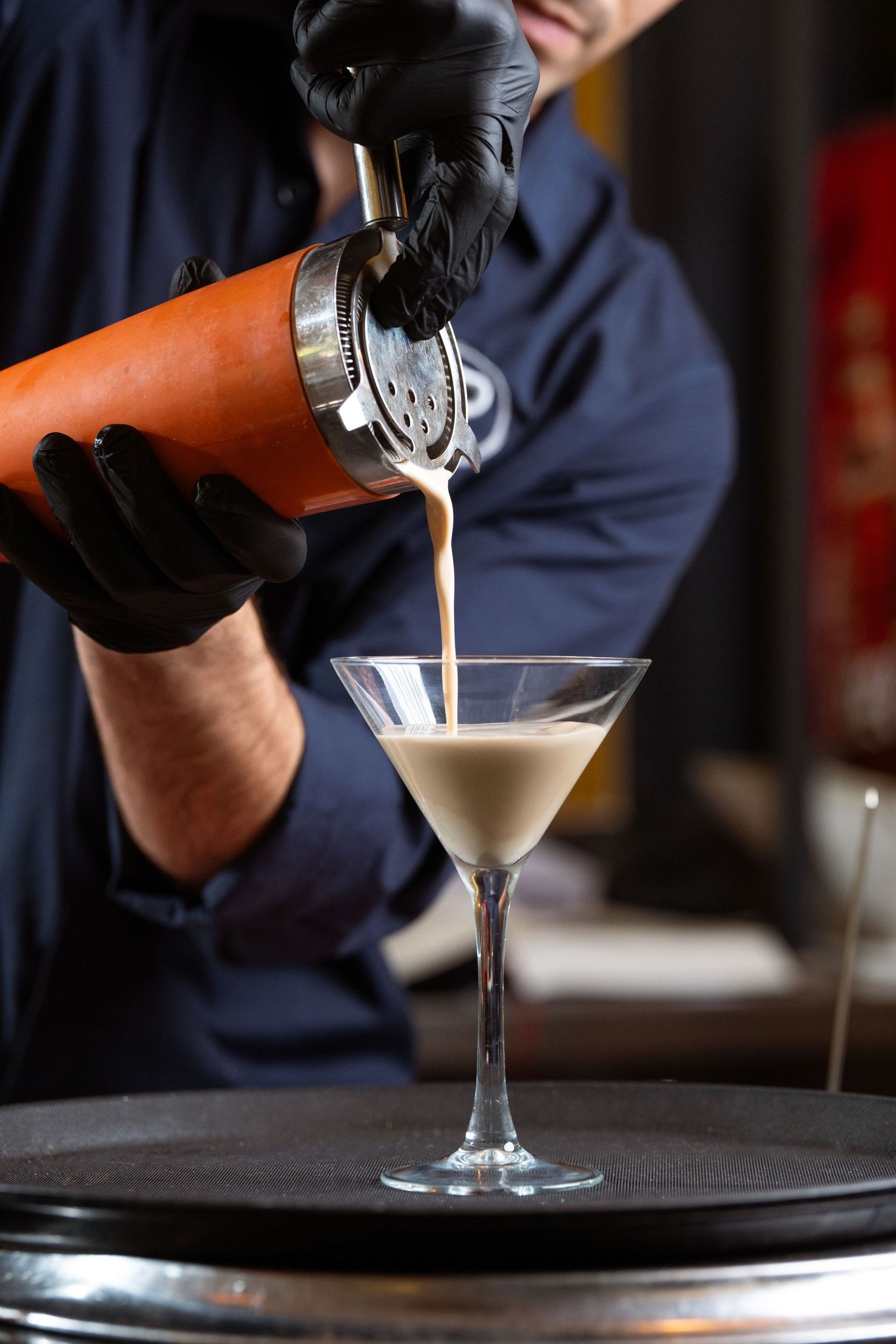 primer plano de un bartender sirviendo una copa en un bar. Se trata de una foto para las redes sociales del negocio.