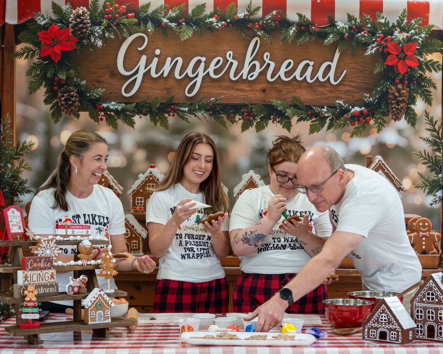 Family decorating gingerbread houses together at a festive Christmas holiday display with seasonal decorations.