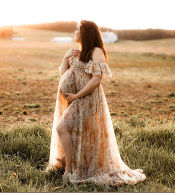 Flowy lace maternity dress captured during golden hour in a rustic field setting.