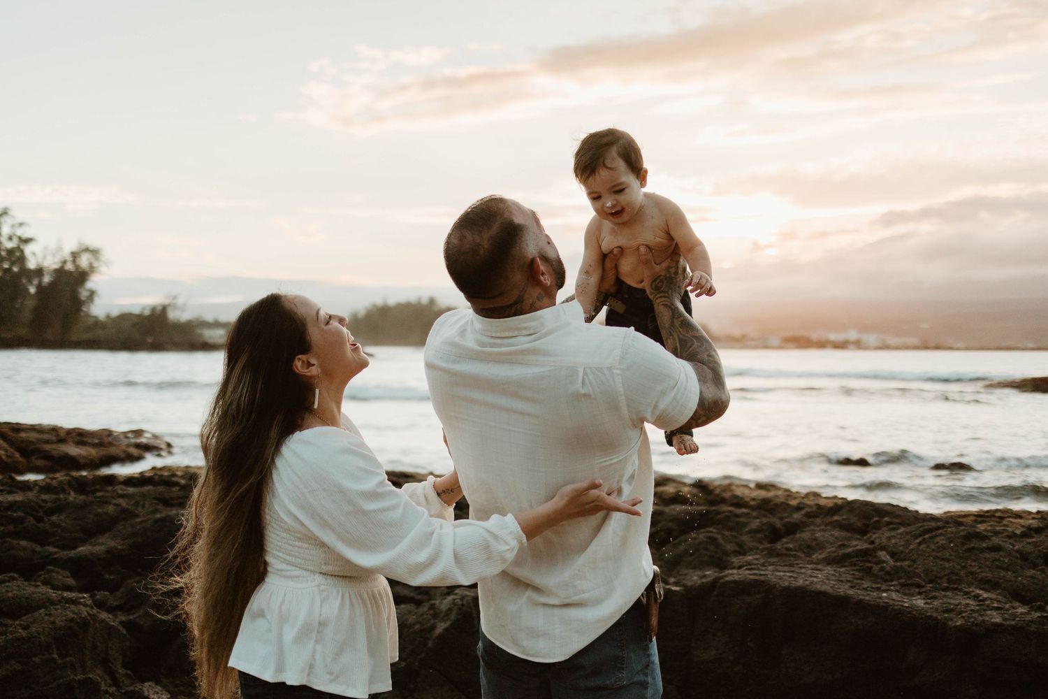 A tender family portrait taken on rocky beach shores during golden hour.