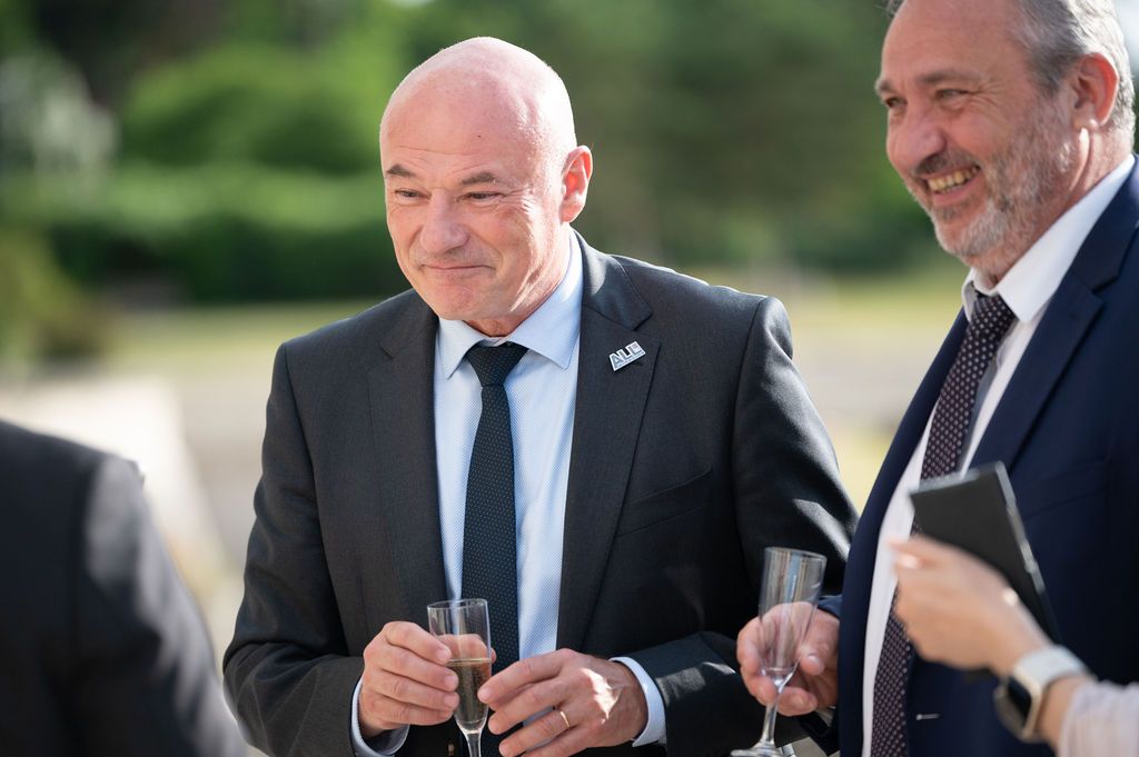 Portrait pensif d’un dirigeant, verre de champagne, forêt lointaine en arrière‑plan.
