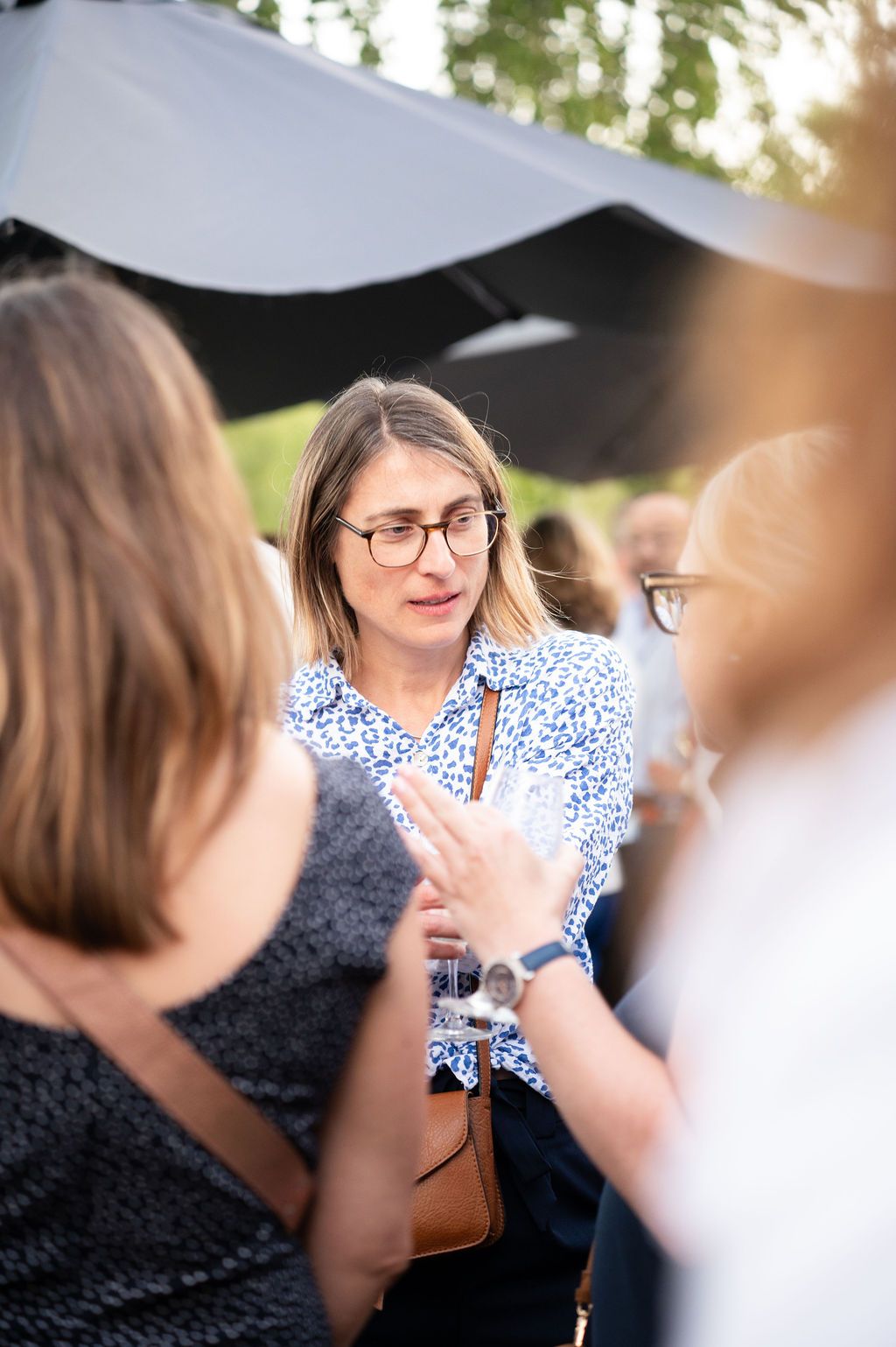 Une femme élégante au sourire bienveillant partage un moment avec ses pairs lors de la soirée d’entreprise.