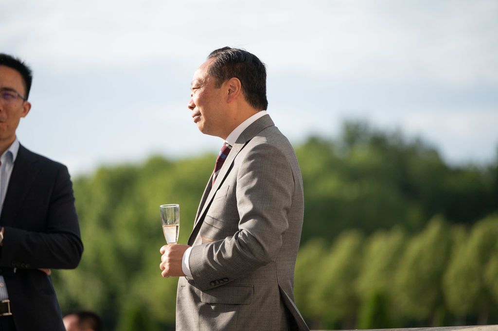 Dirigeants souriant et champagne, ambiance conviviale sur la terrasse face aux jardins.