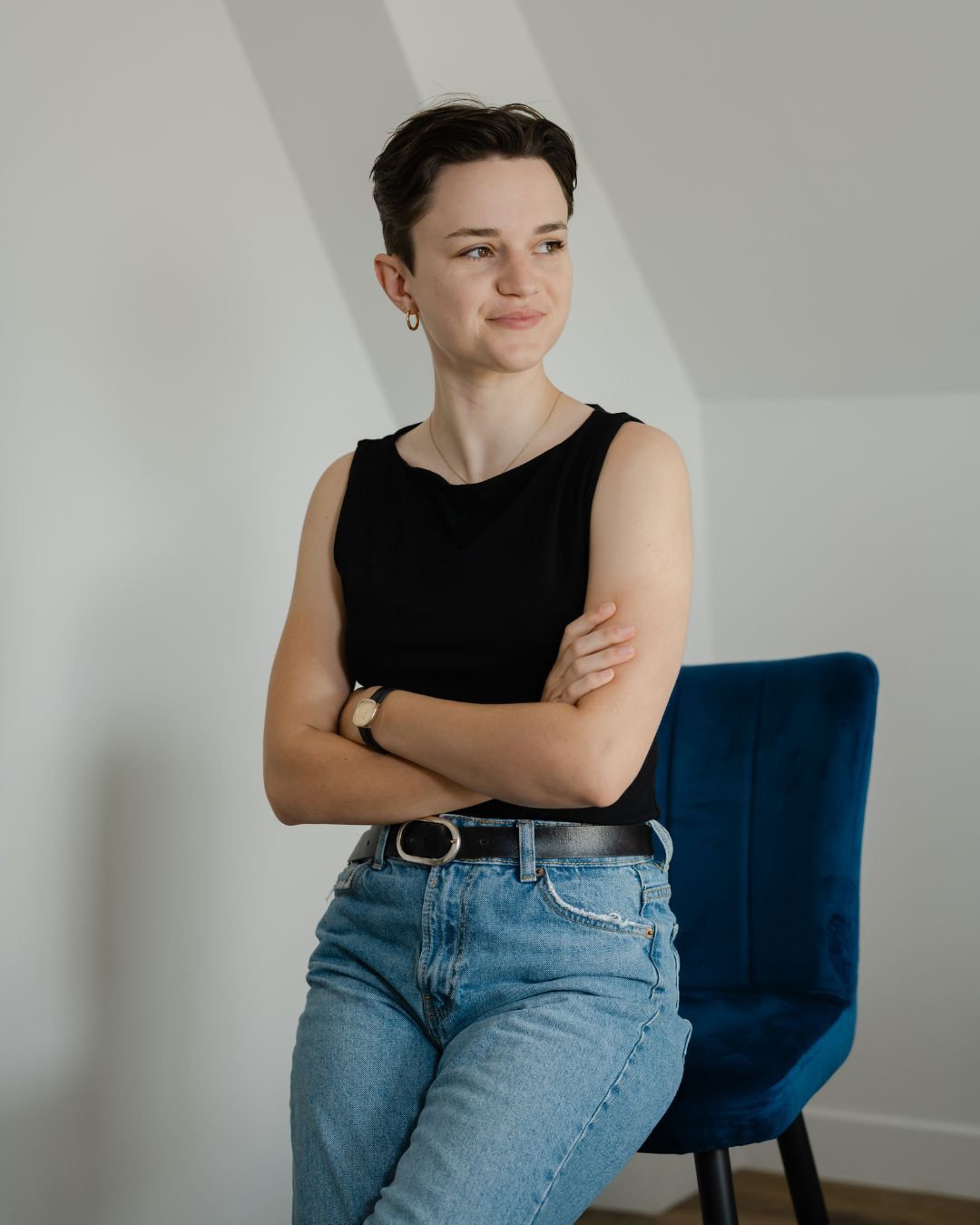 Portrait d’Amandine Derimay, photographe documentaire en Centre-Val de Loire, assise sur une chaise bleue dans une lumière naturelle douce