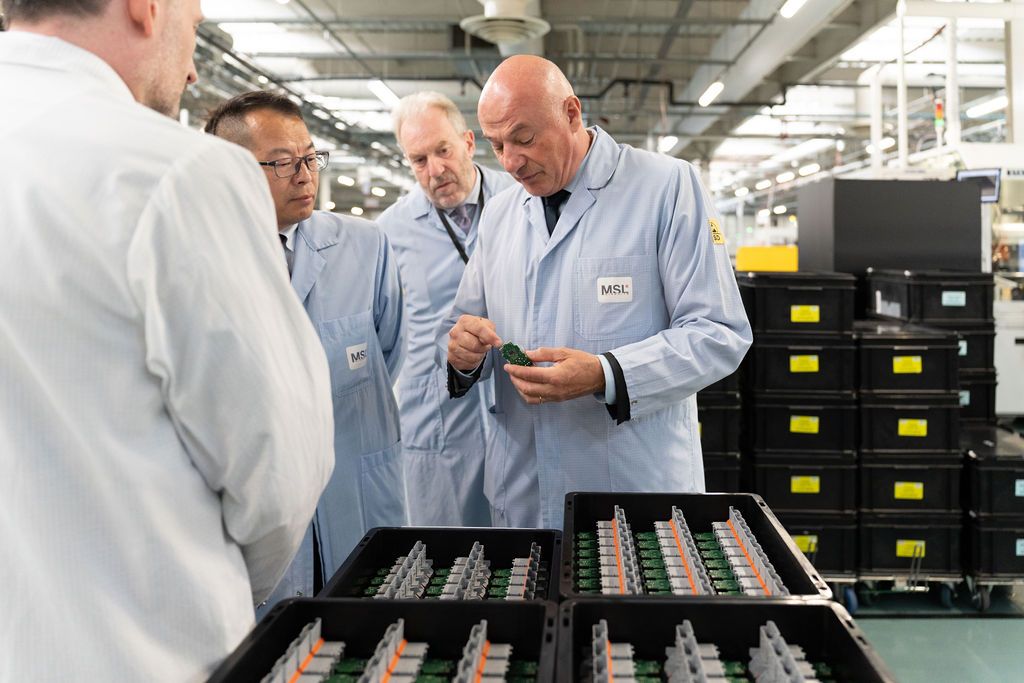 Ingénieur présente un procédé de production lors d’une visite d’usine — valorise expertise et communication interne