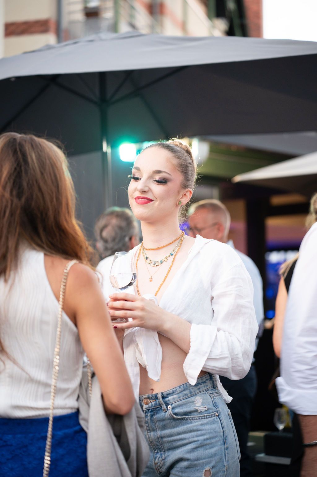 Une femme élégante au sourire bienveillant partage un moment avec ses pairs lors de la soirée d’entreprise.