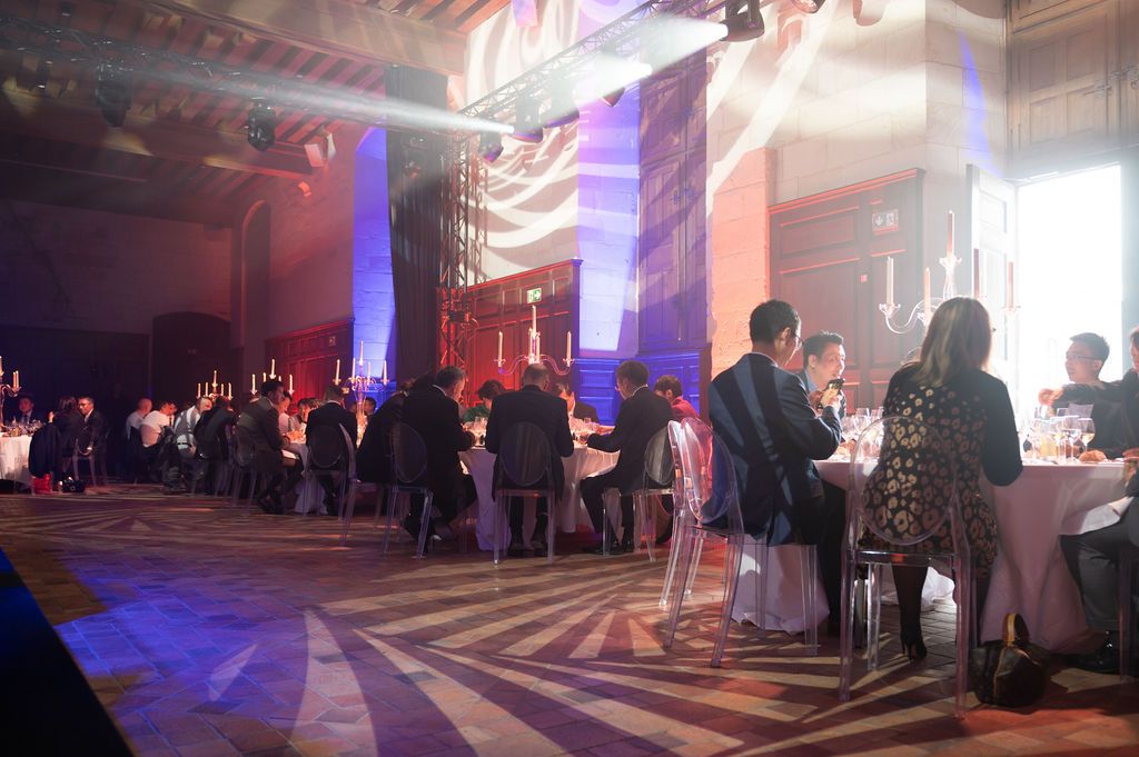 Grande salle du Château de Chambord remplie d’invités attablés, ambiance chaleureuse et décor lumineux pour le gala.