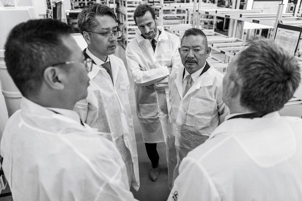 Dirigeants internationaux échangent en pleine ligne de production — reportage corporate sur leadership et innovation industrielle
