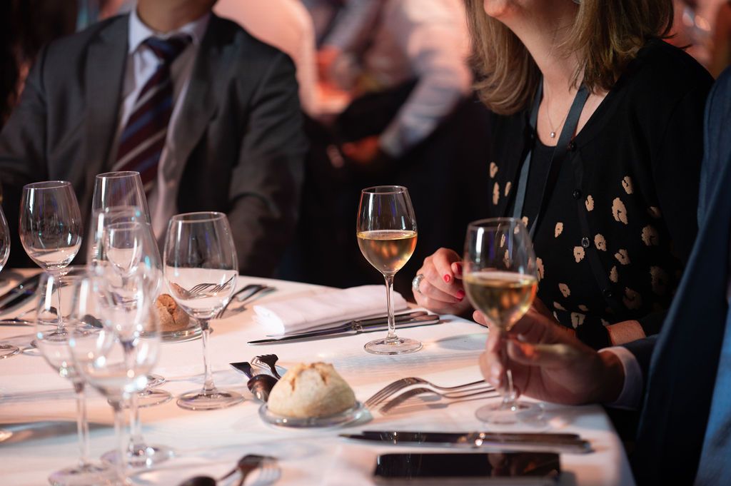 Verres de vin blanc à la main, invités élégants échangent autour d'une table dressée pour un dîner au Château de Chambord.