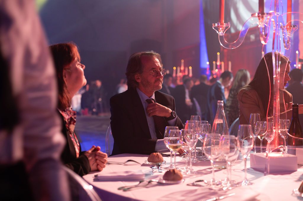 Un invité élégant plongé dans ses pensées lors du dîner de gala à Chambord.