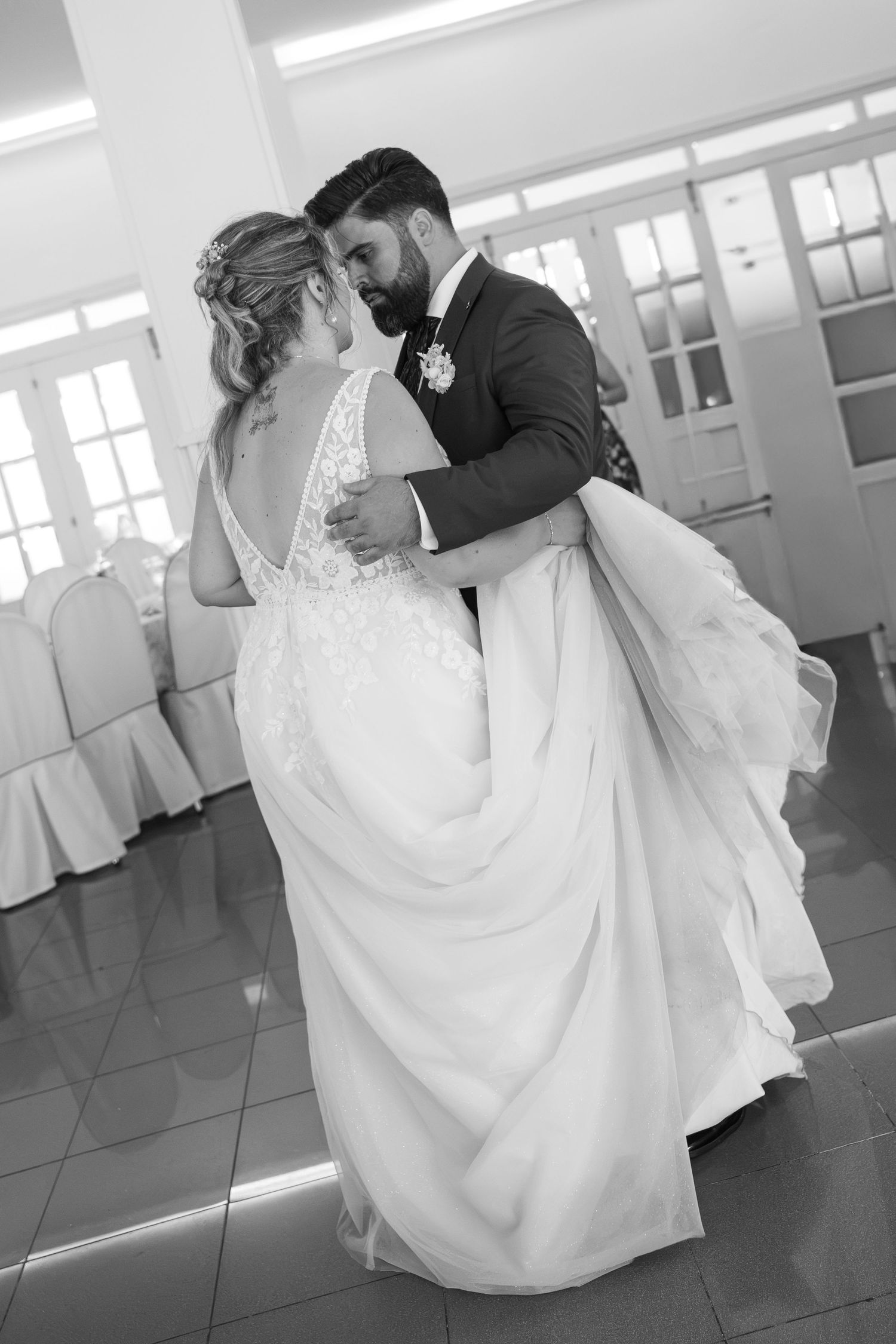 Black and white photo of a bride and groom sharing their first dance at a wedding reception.