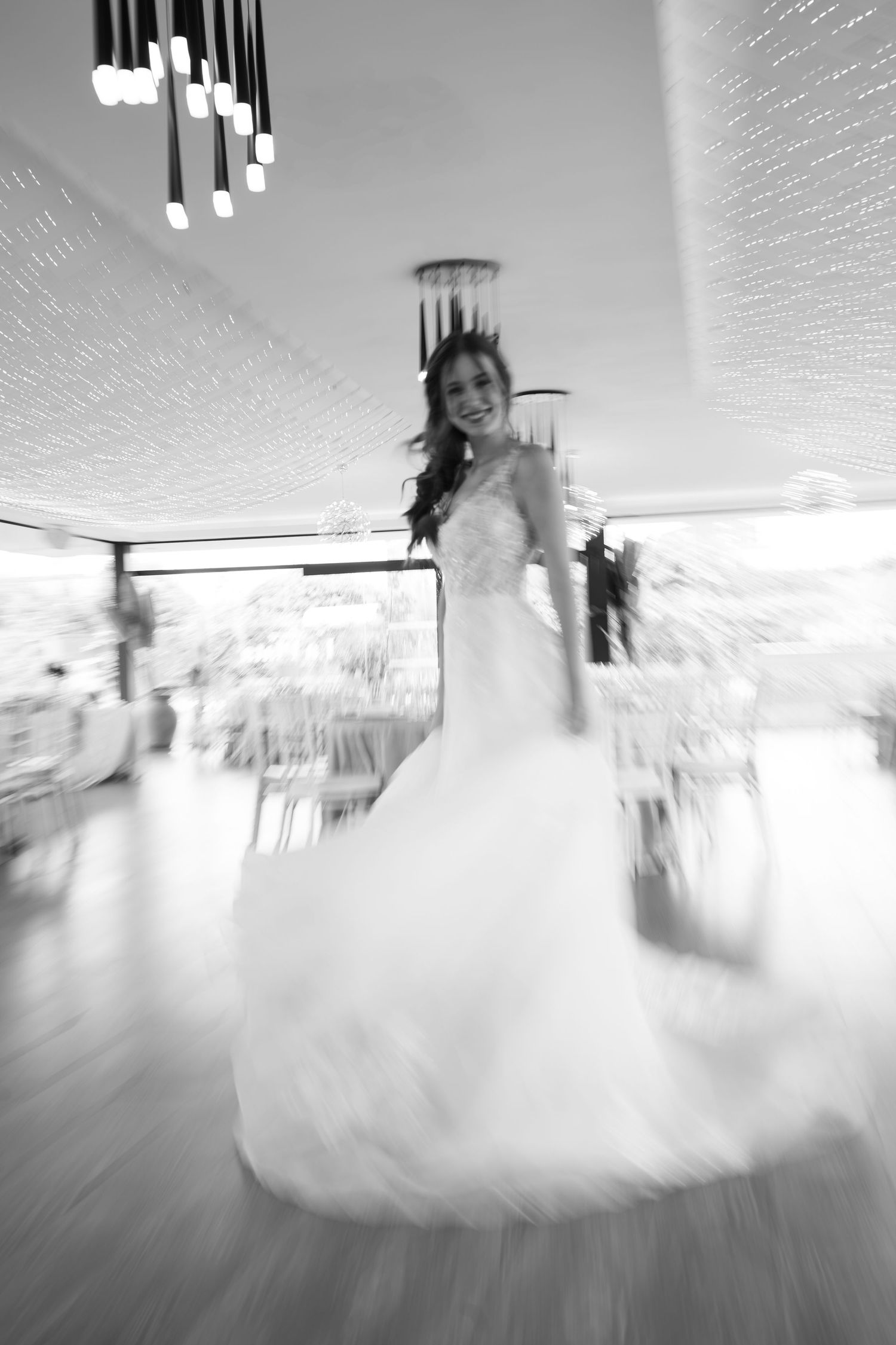 Black and white photo of a smiling bride in a flowing wedding dress spinning on the dance floor.