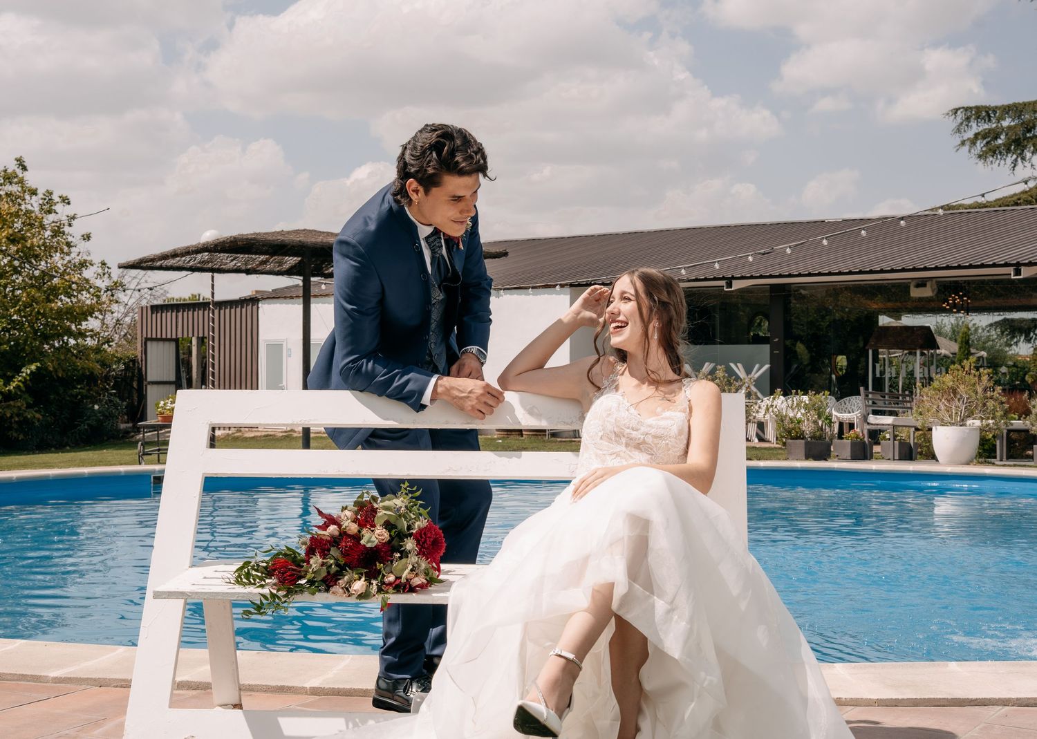 Bride and groom sharing a happy moment by a swimming pool at a wedding venue.