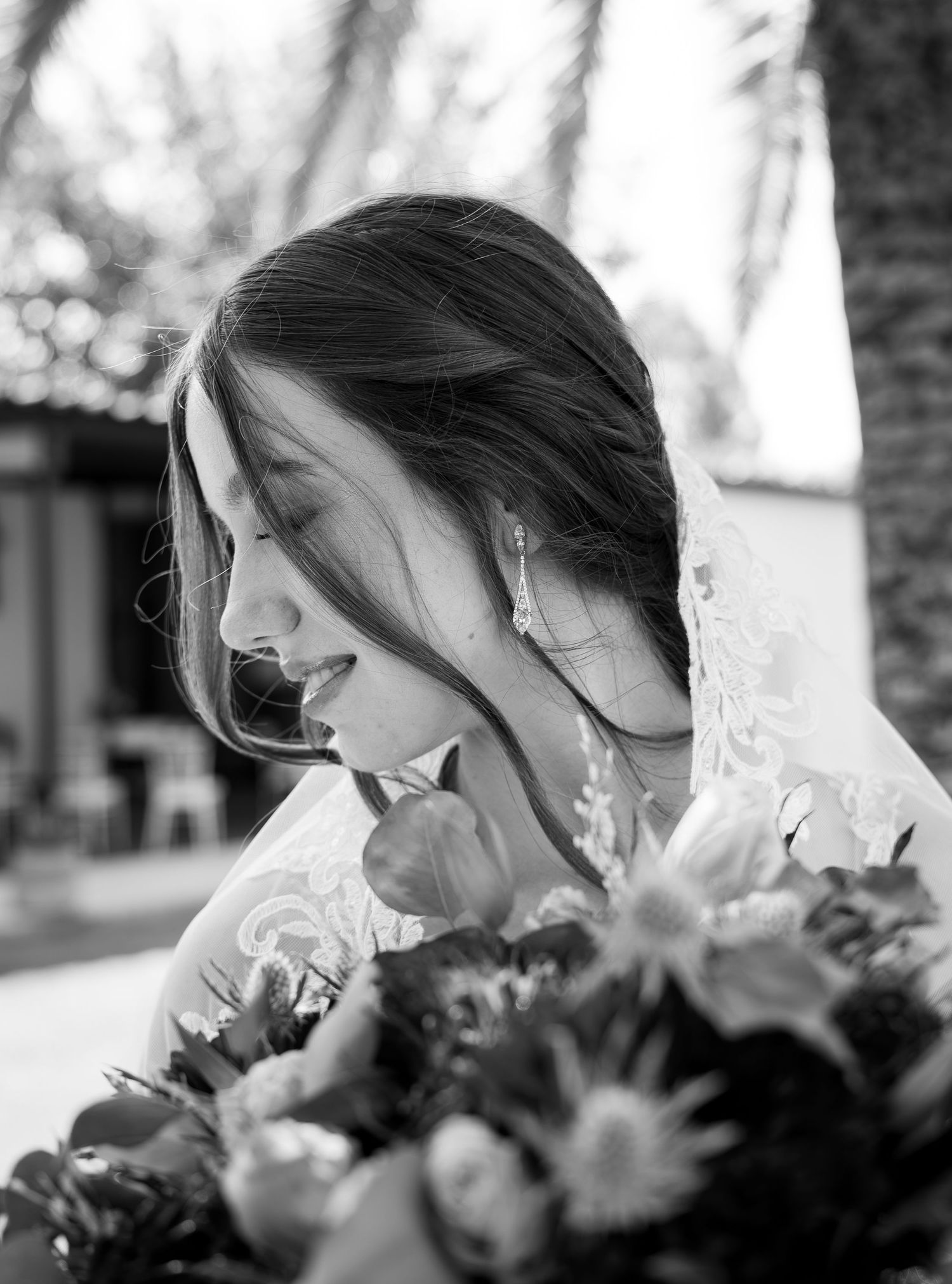 Black and white photo of a bride smelling her wedding bouquet of flowers.