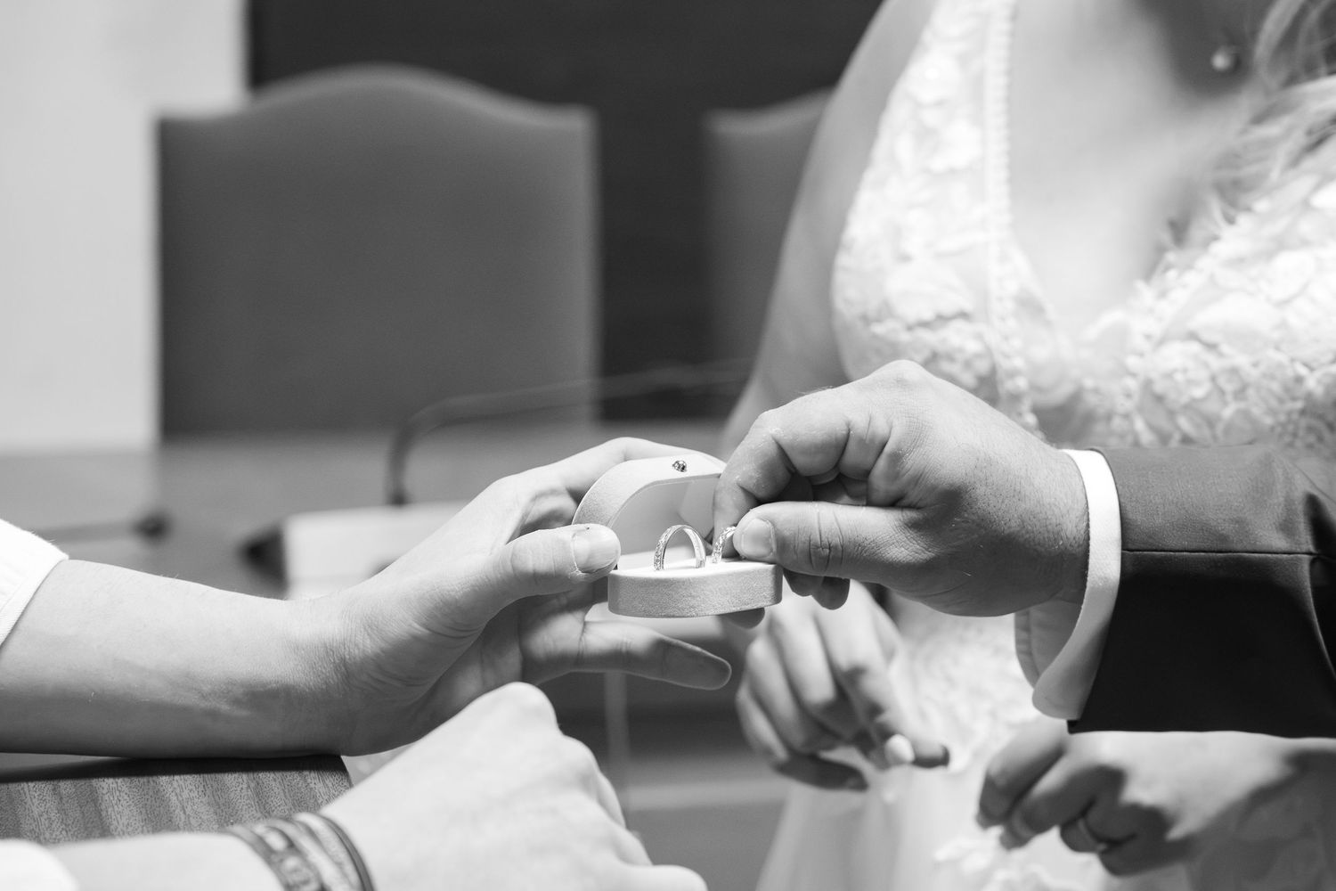 Black and white photo of a couple exchanging wedding rings during a ceremony.