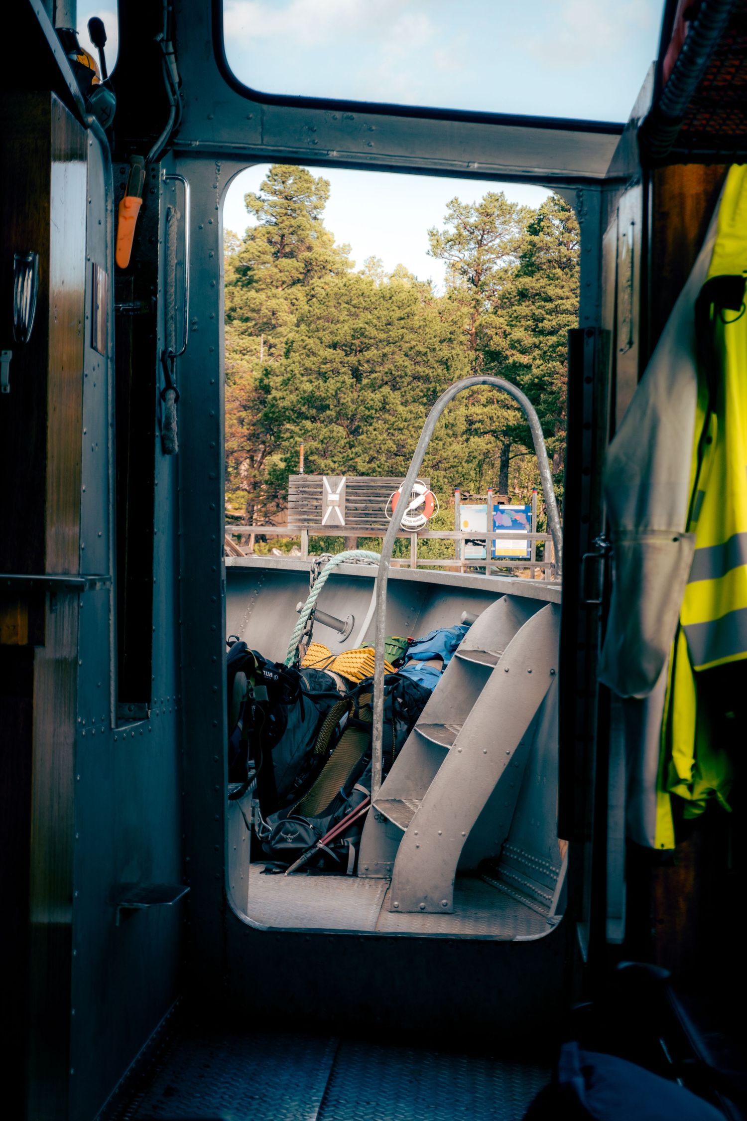 View through open vehicle door showing backpacks and outdoor gear with trees in background.