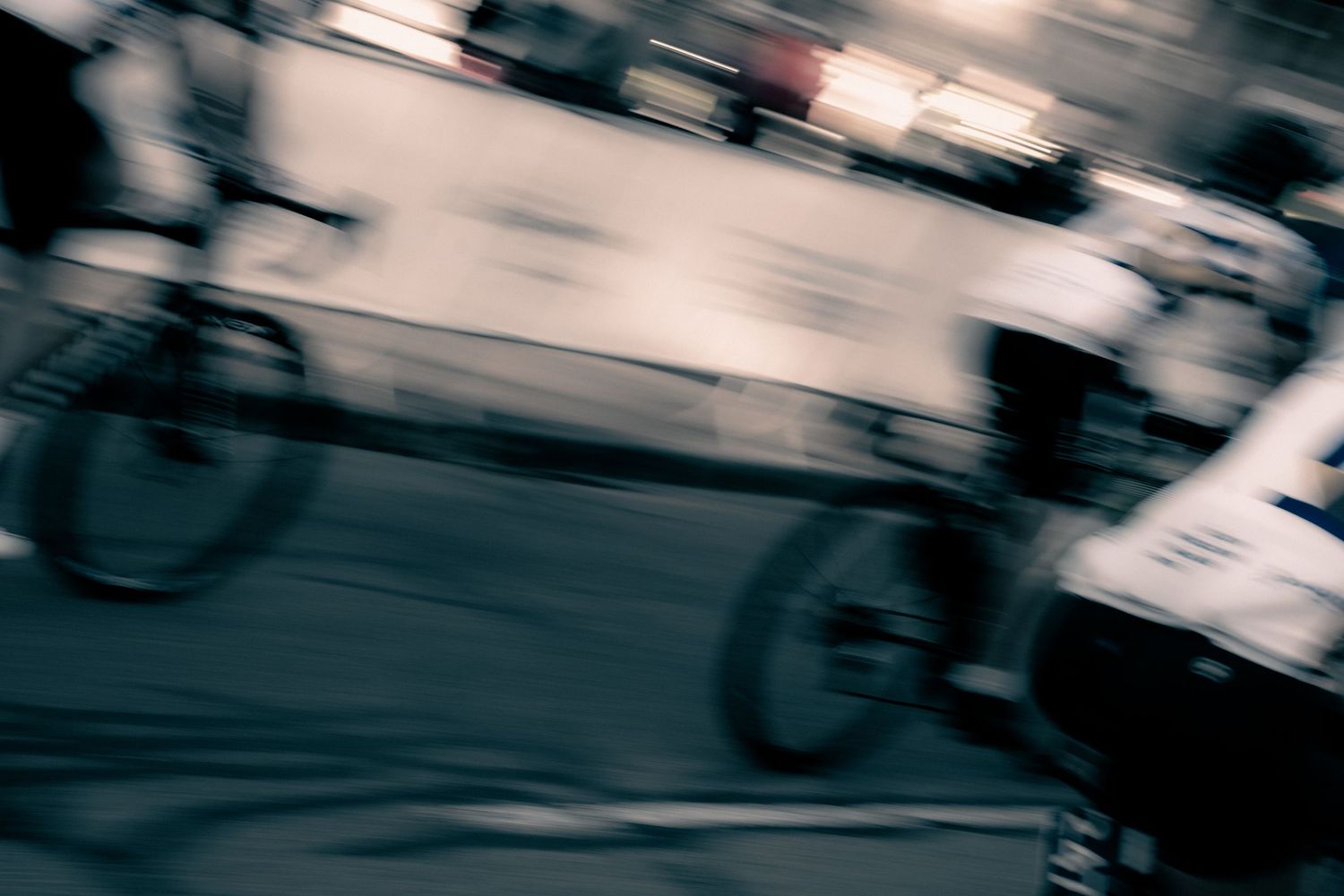 Blurred motion shot of cyclists racing on a street at night, capturing speed and movement.