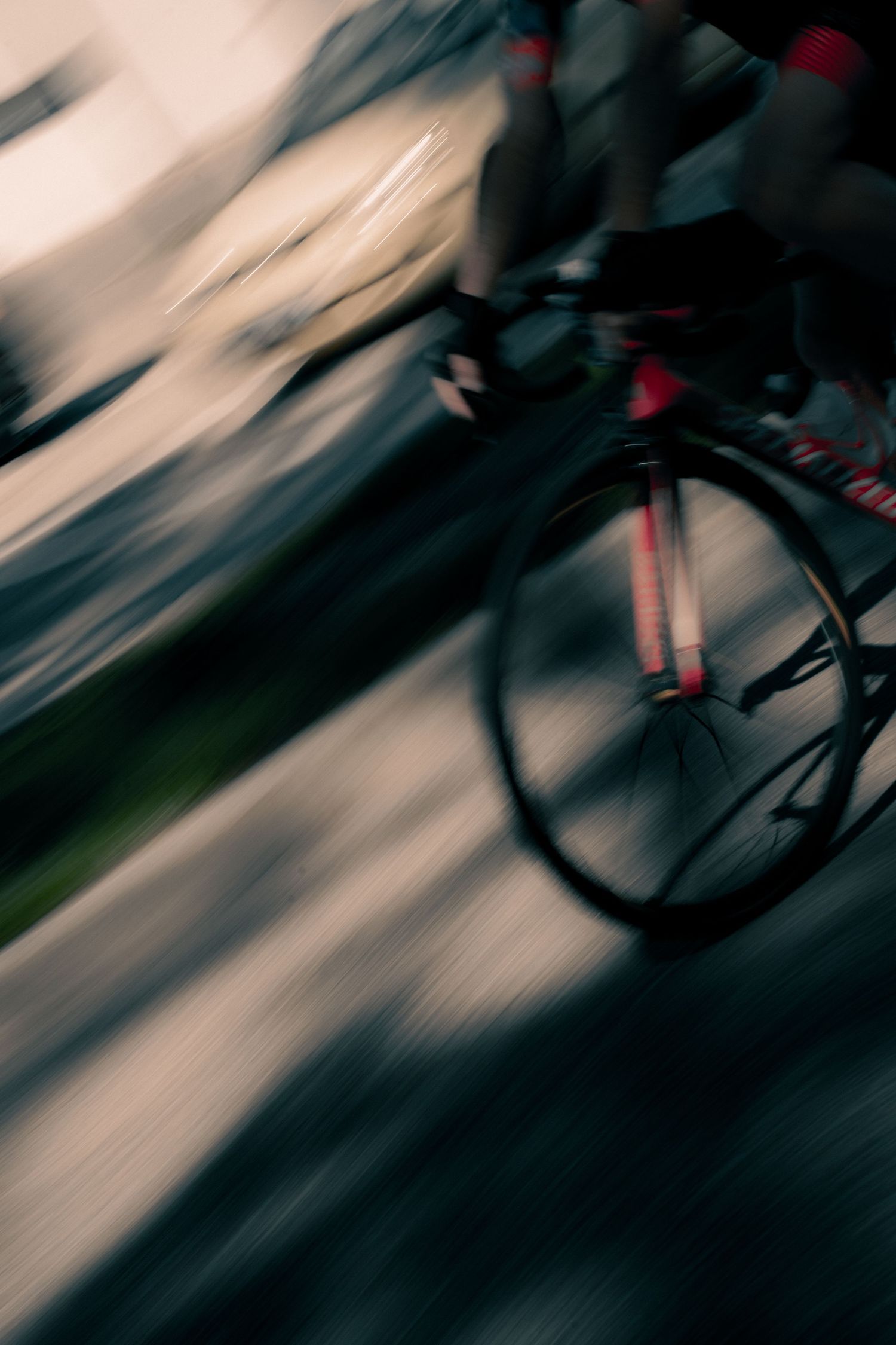 Blurred motion shot of a cyclist racing on a road, captured with panning technique showing speed and movement.
