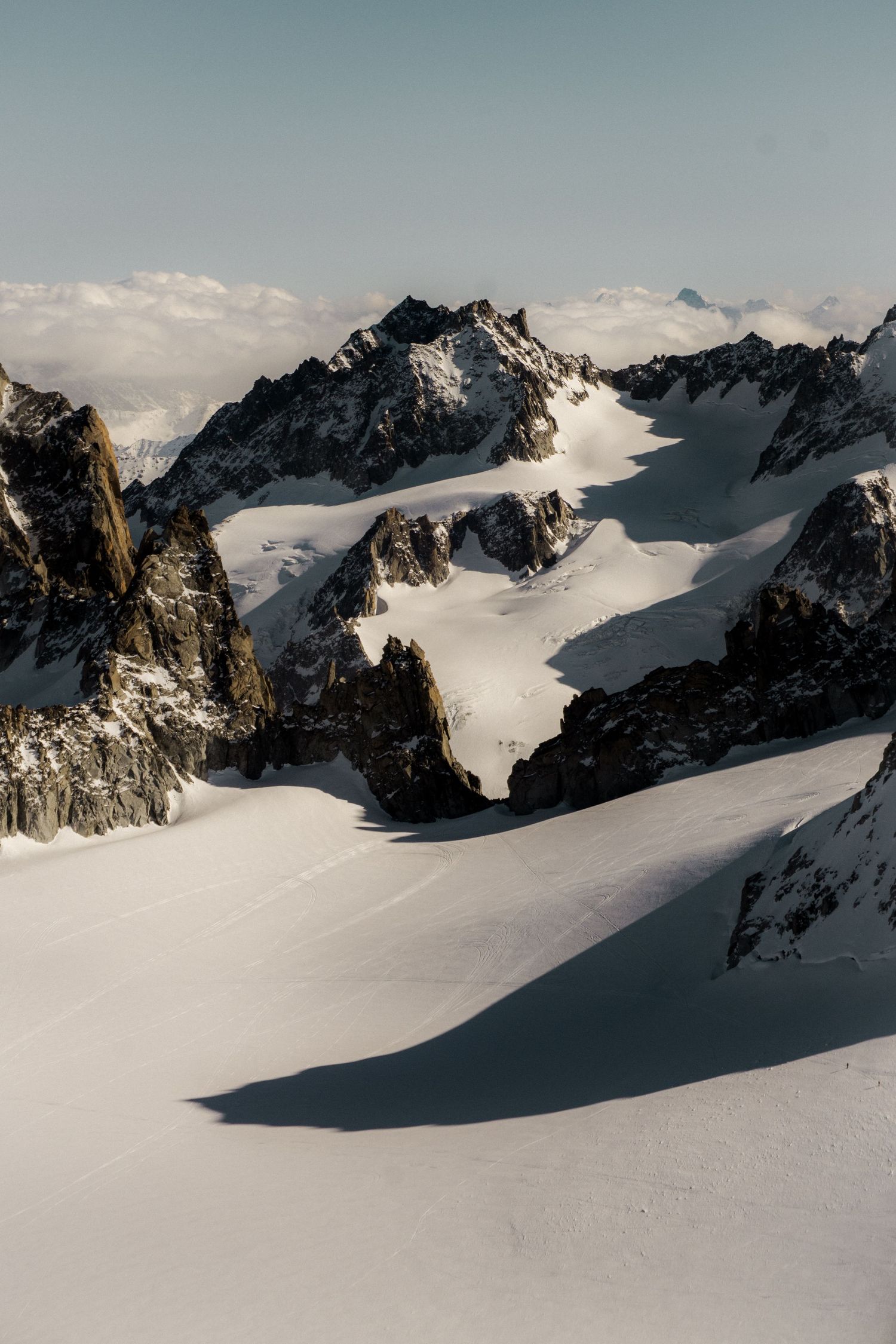 Snow-covered alpine peaks with dramatic rocky ridges and glaciers under a clear sky in a stunning mountain landscape.