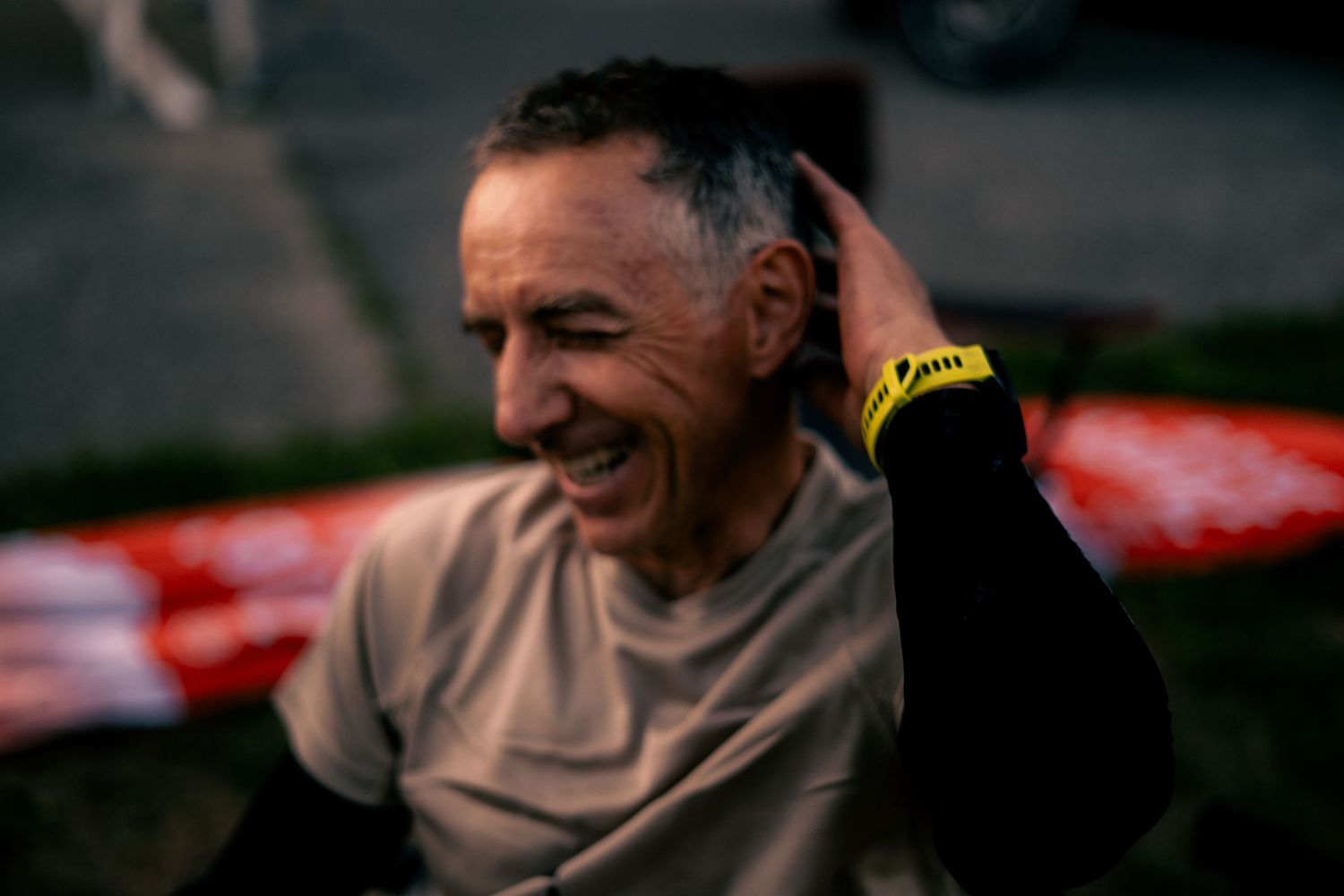 Smiling older male athlete with gray hair wearing a yellow wristband after a race.