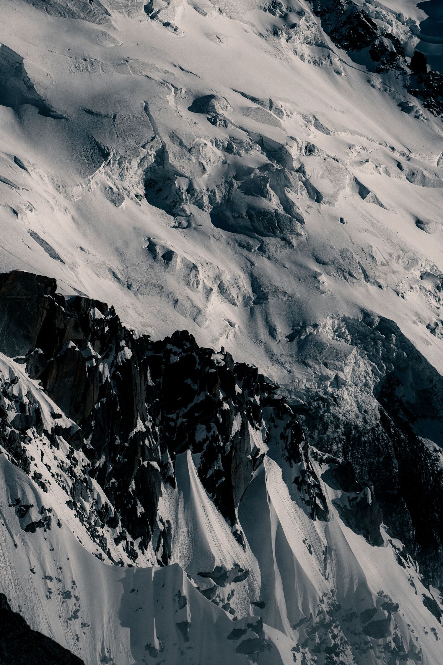 Black and white close-up of jagged snow and ice formations on a steep Alpine mountain face.