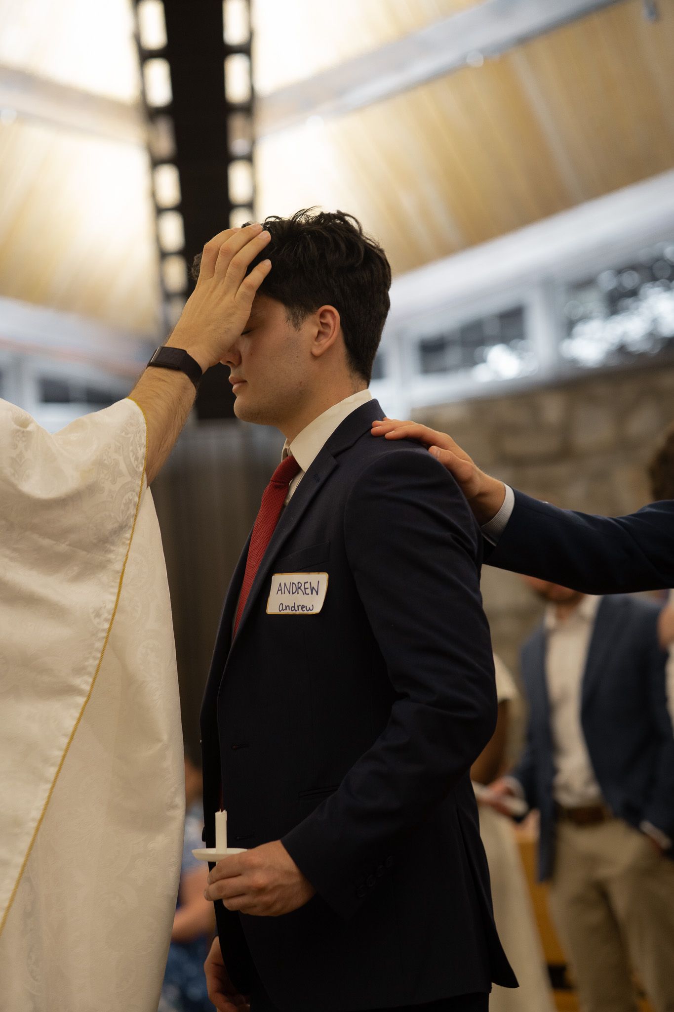 Priest anointing a young man with chrism oil during a confirmation Mass in Athens, GA.