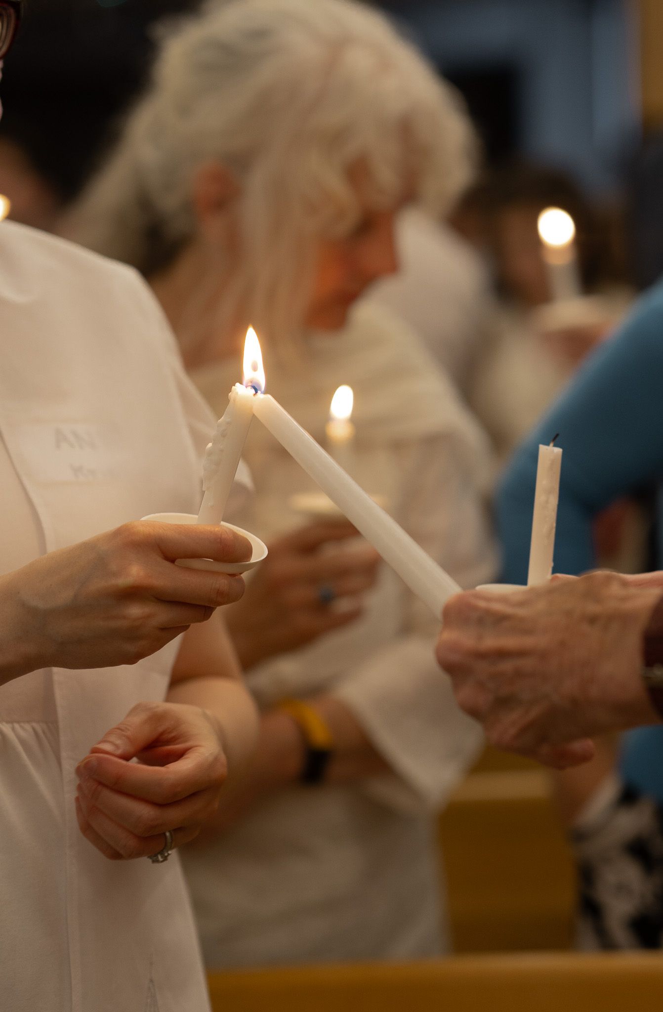 People holding lit white candles during a Catholic Easter Vigil Mass in Athens, GA.