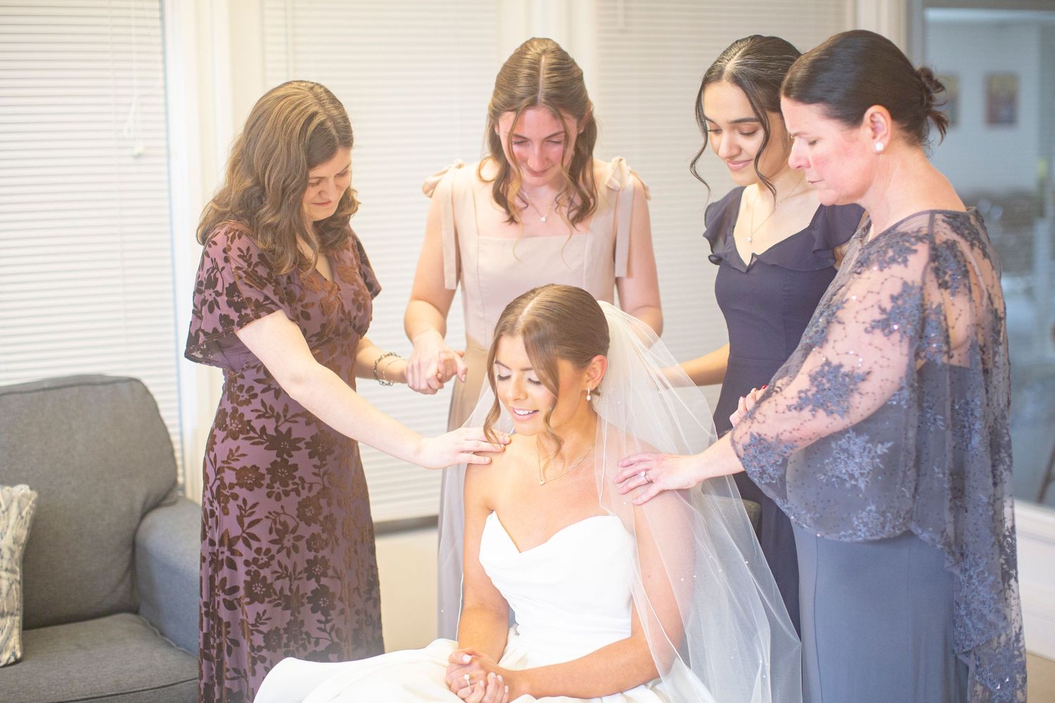 Catholic bridesmaids helping bride with veil while she sits in white wedding dress during bridal preparation in Athens, GA.